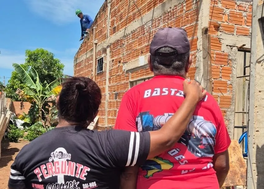 O morador Raimundo Vieira da Cunha e sua filha Fabiana acompanhando a montagem das telhas na casa atingida pelo vendaval. Foto: Flora Pereira